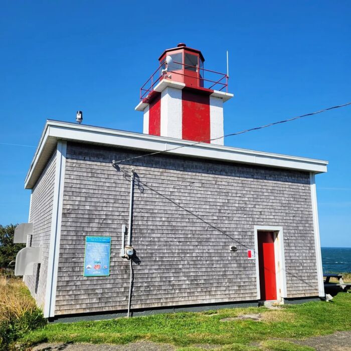 small building with lighthouse on top overlooks the water